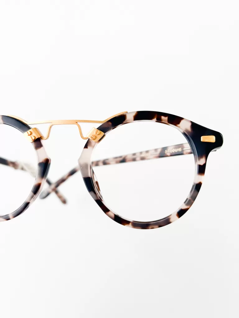 This image features a pair of sophisticated eyeglasses with a classic round frame design. The frames are crafted from high-quality acetate with a tortoiseshell pattern in shades of brown and black, enhanced with elegant gold accents along the bridge and the upper part of the rims. This design combines a timeless aesthetic with a touch of modern elegance, making these glasses suitable for both formal and casual settings. The clear, large round lenses promise a wide field of vision, catering to both style and functionality. The white background serves to highlight the intricate details and rich colors of the frames.