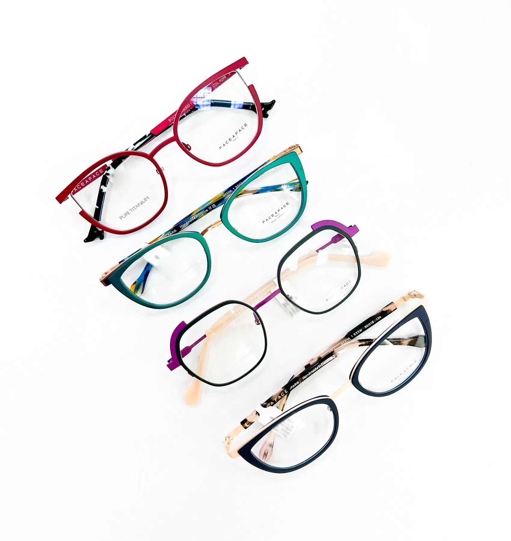 A collection of six colorful eyeglasses laid out in a circular pattern on a white background. The glasses frames vary in colors and styles, featuring vibrant hues like red, green, purple, and blue, each with unique patterns and designs.