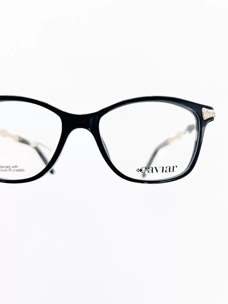 This image features a pair of elegant black eyeglasses, demonstrating a sophisticated design suitable for reading glasses. The frames are sleek, crafted from high-quality acetate with a smooth, glossy finish that enhances their refined appearance. The standout detail is a small, tasteful embellishment on the upper corner of one side of the frames, which consists of a cluster of tiny Swarovski crystals. This subtle yet luxurious addition adds a touch of sparkle and distinction, making the glasses not only functional for reading but also a fashionable accessory. The branding "Caviar" is discreetly placed on the lens, indicating the luxury and quality associated with the brand. The white background of the image emphasizes the clean lines and chic aesthetics of the glasses, appealing to those who appreciate a blend of classic style and contemporary elegance in their eyewear.