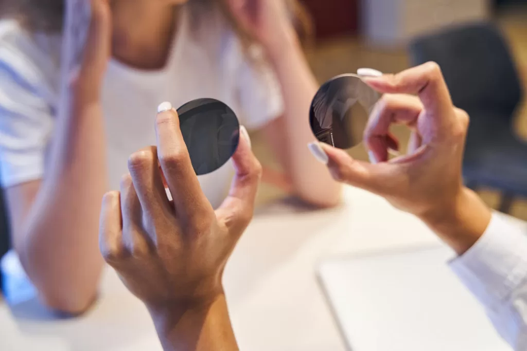 Female optician hands holding new round lenses for eyeglasses