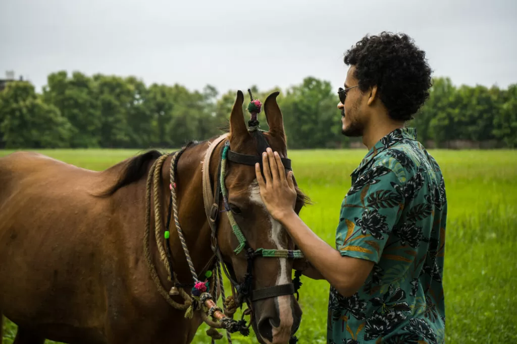 Man wearing luxury sunglasses while petting his brown horse