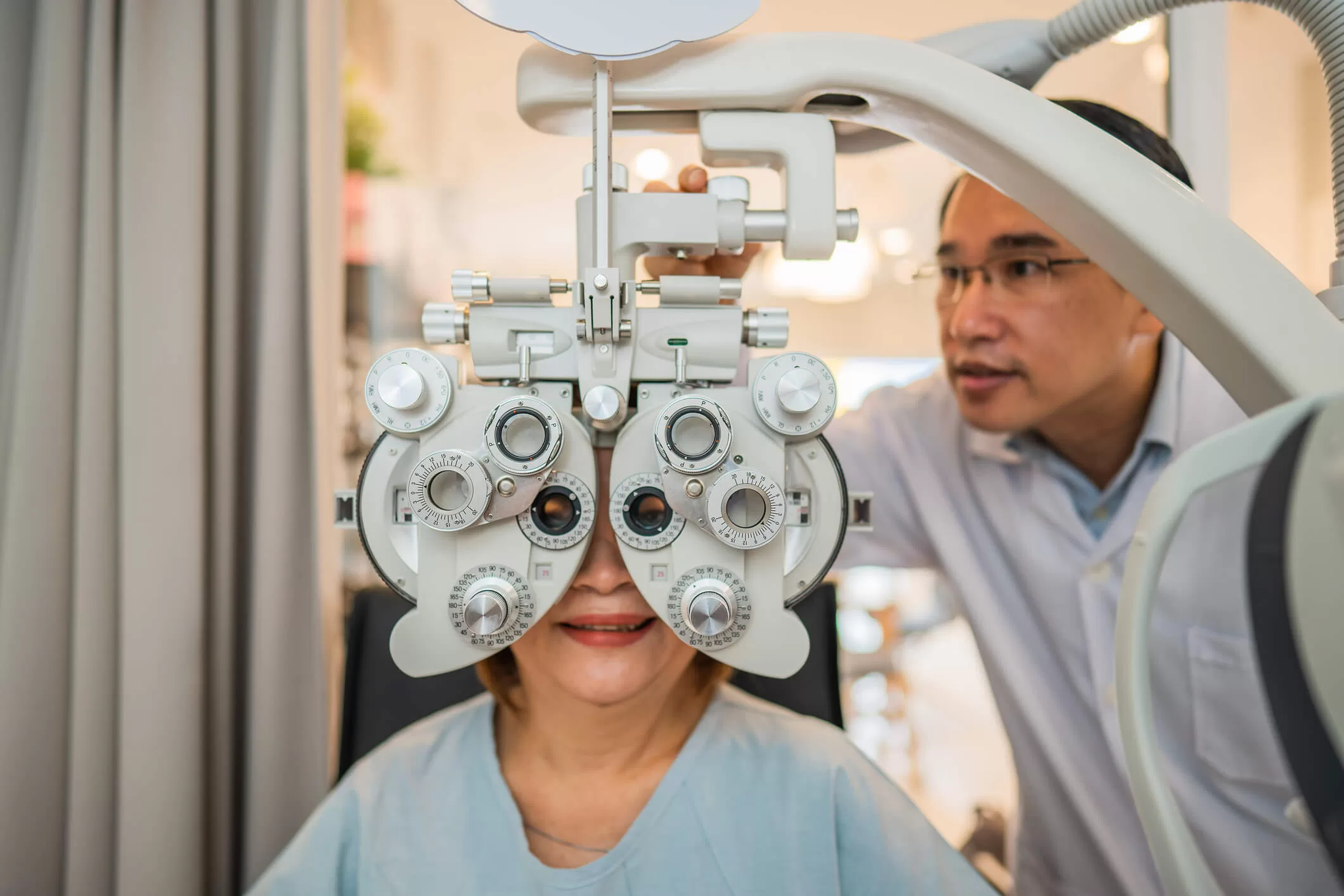 Dr. Richard Le using phoropter to check eyesight value for client eyeglasses