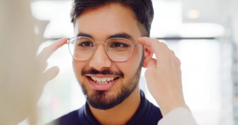 Man trying on round steel eyeglass frames during eyewear fitting