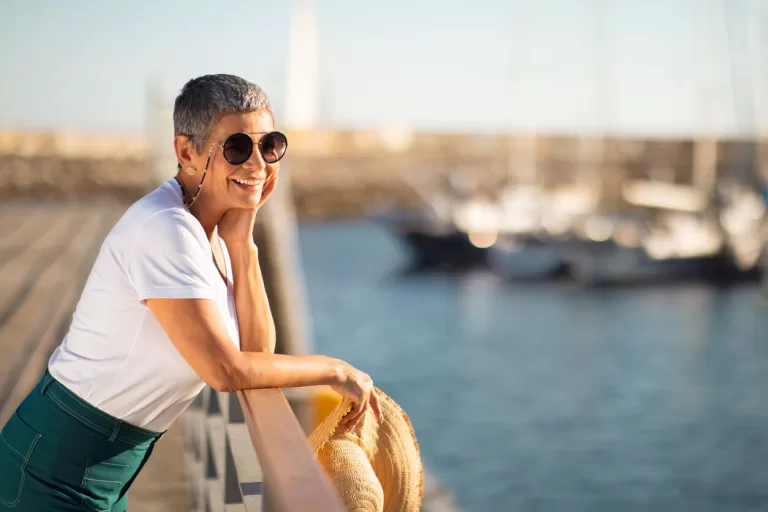 Woman wearing luxury round sunglasses by marina on sunny day
